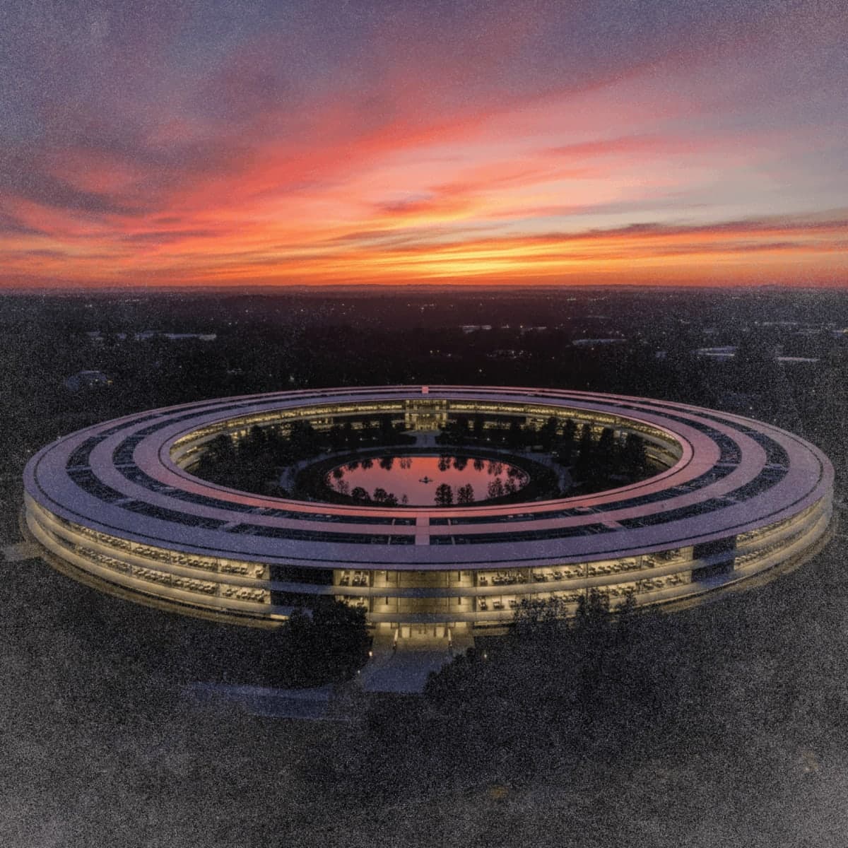 Apple Park headquarters at dusk with lights turning off across sections of the circular building, representing executive departures