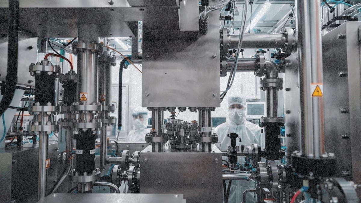 Industrial lithography prototype machine in a laboratory setting with engineers observing from behind safety glass