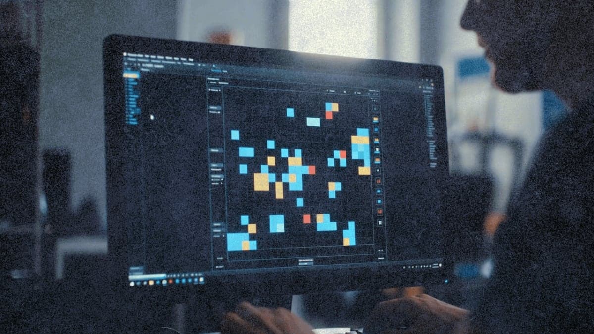 Computer screen showing colorful grid puzzle from ARC-AGI benchmark test with person's hand near keyboard