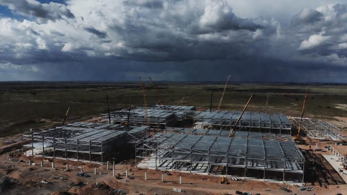 Empty data center construction site with steel framework and idle cranes against an overcast sky