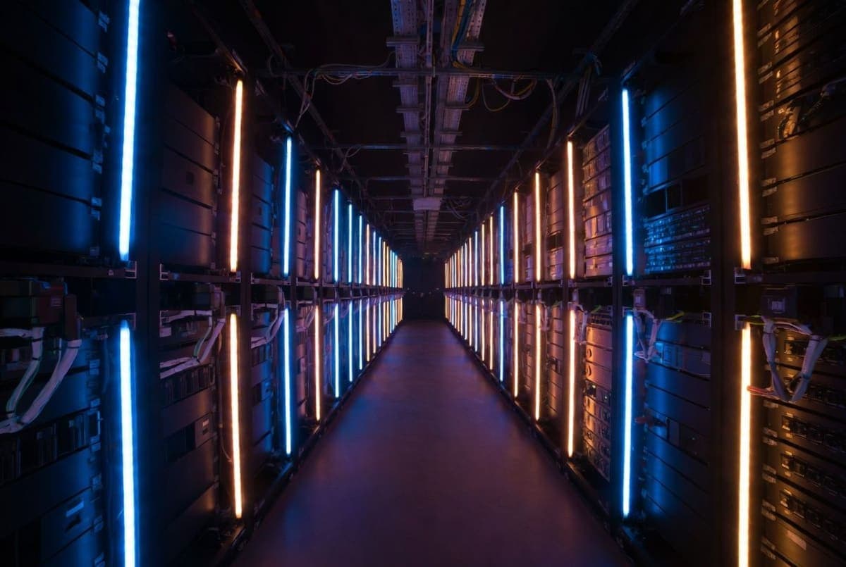 Abstract visualization of interconnected compute nodes forming a global network, bathed in warm amber and cool blue tones against a dark background