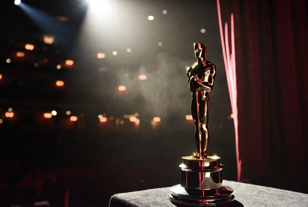 Oscar statuette on a dark stage with stage lights diffused behind it