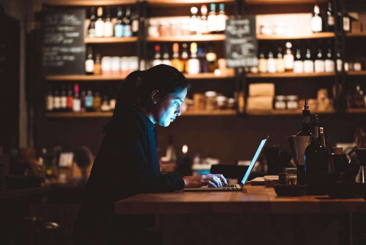 Small business owner working late at night on a laptop in a dimly lit independent shop