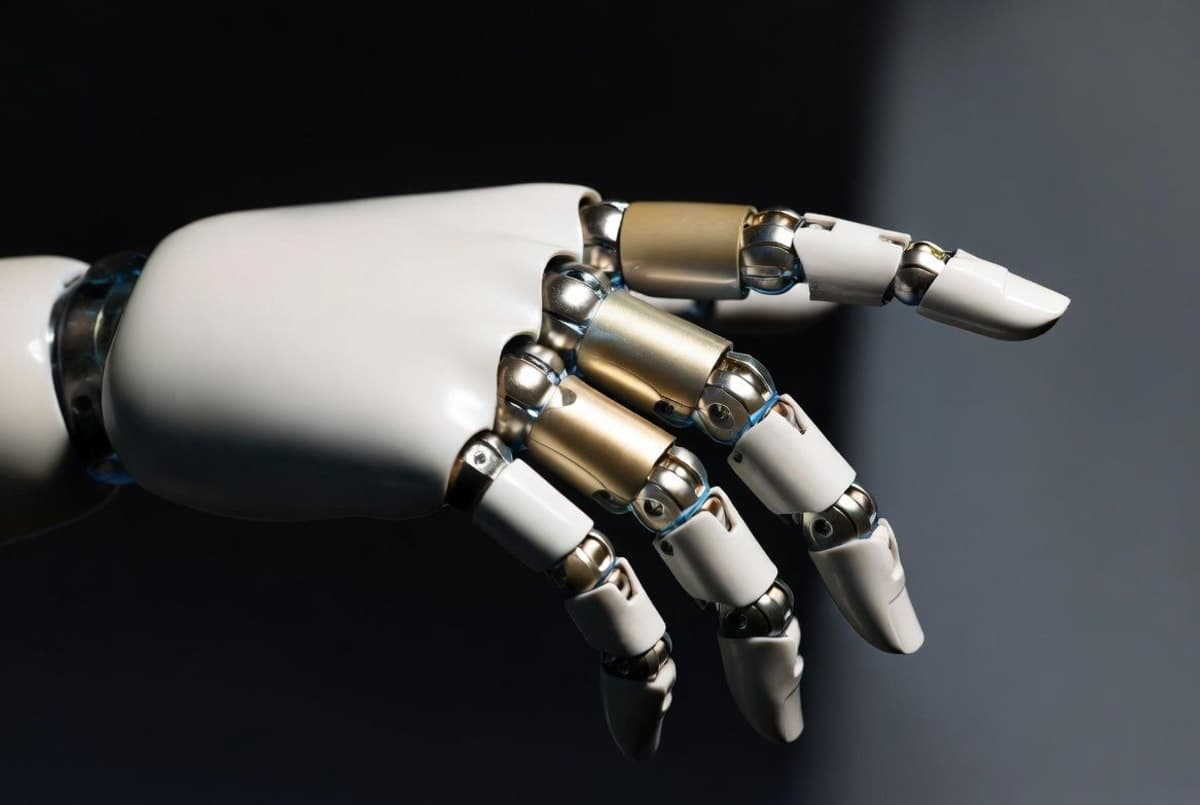 Close-up of a sleek bionic robotic hand with articulated fingers gripping a small object, showing visible joint segmentation against a dark studio background