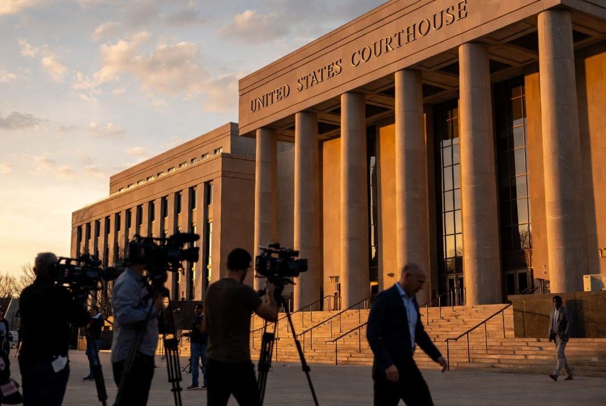 Exterior of a U.S. federal courthouse building with news crews gathered on the steps