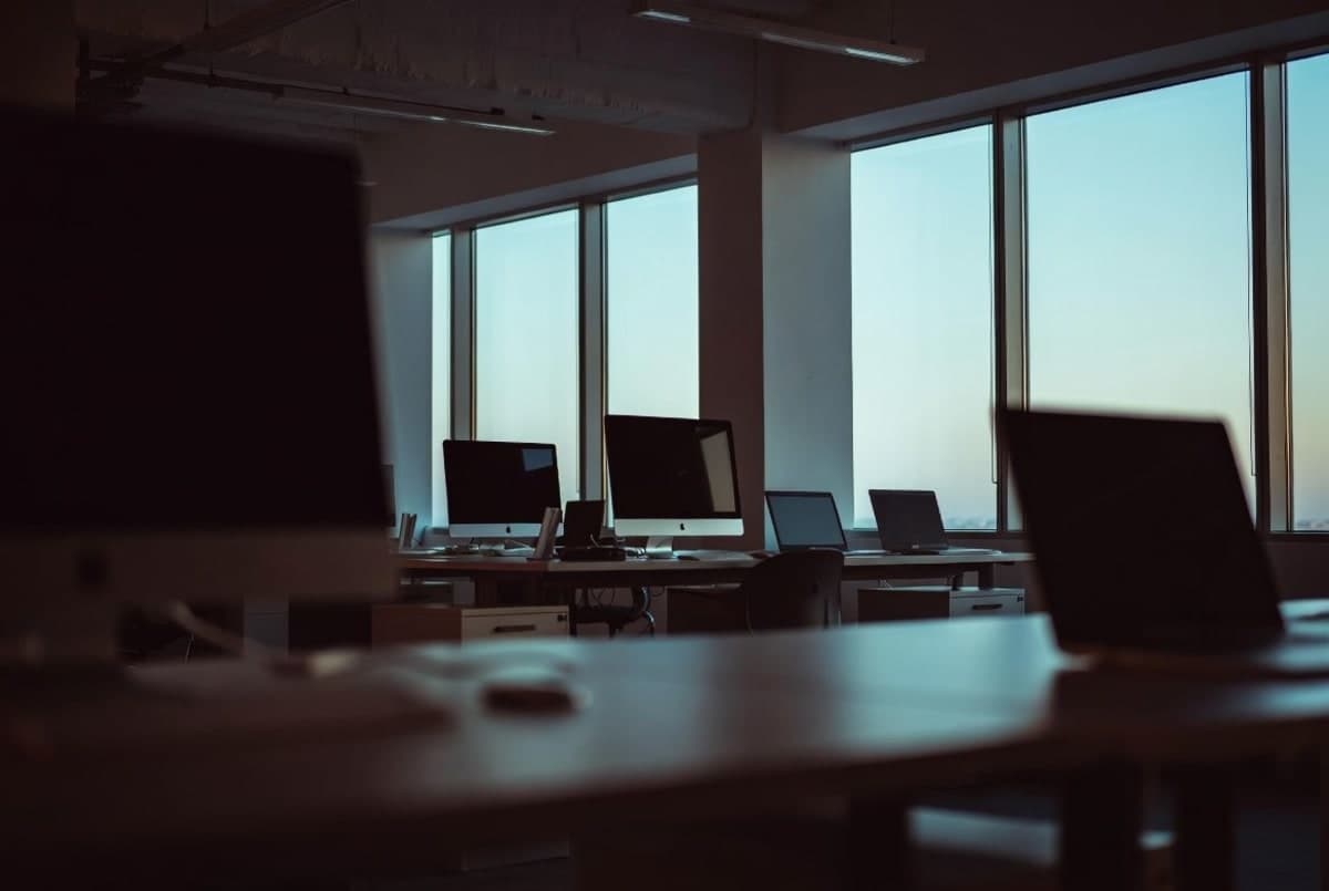 Empty desks in a modern open-plan tech office lit by early morning light