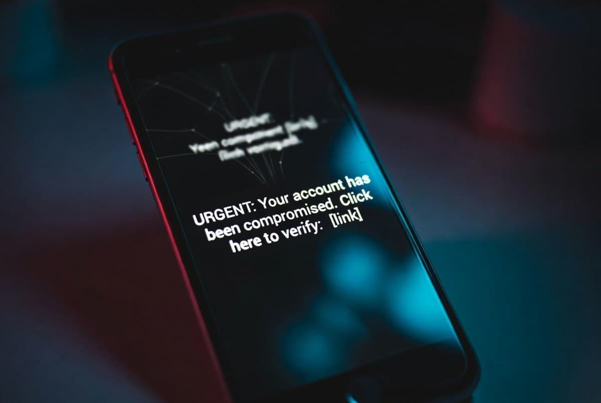 Smartphone displaying a fraudulent text message with a suspicious link against a dark background
