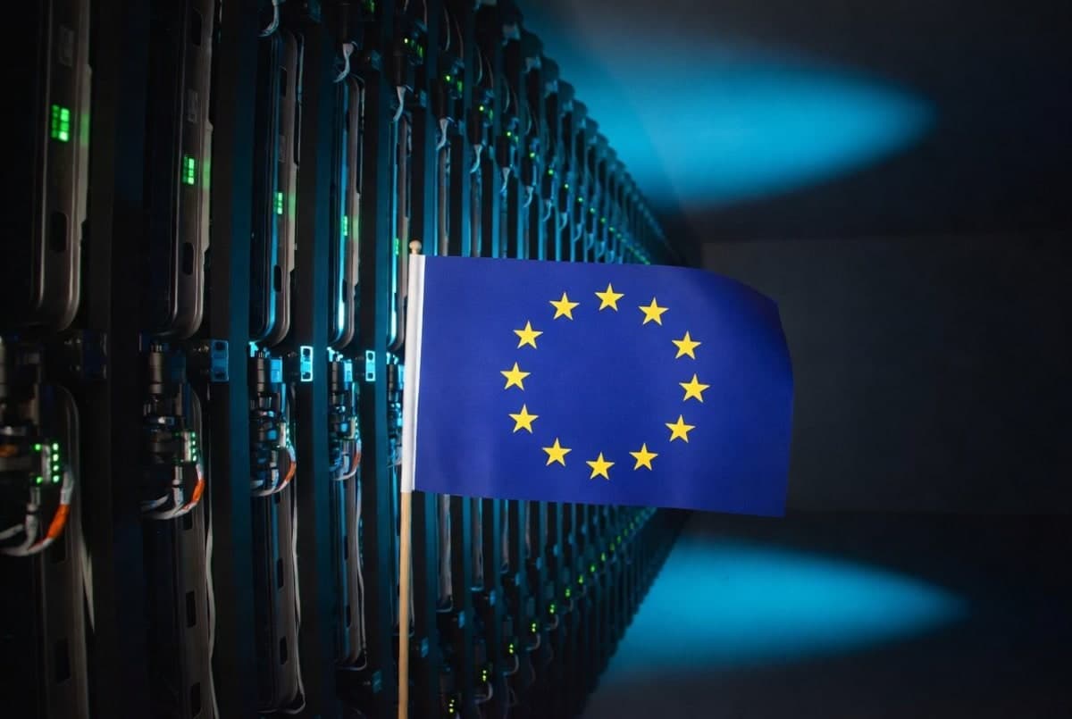 European Union flag beside a darkened data center server room, suggesting restricted access to AI infrastructure