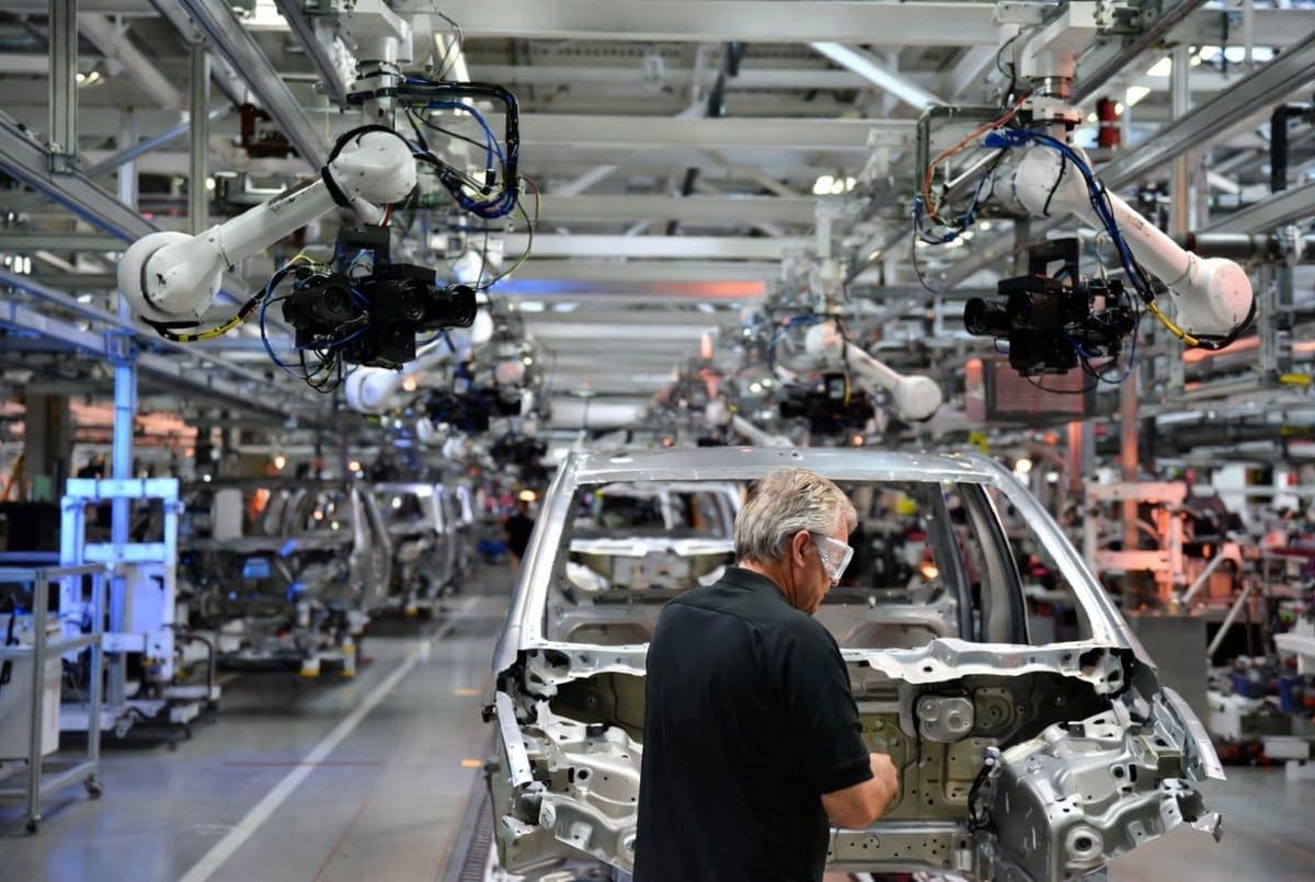 Ford vehicle assembly line with engineers inspecting a partially built truck body
